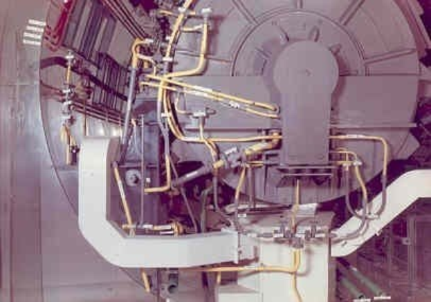 Großes industrielles Accelerator-Gerät mit mehreren verbundenen Komponenten und Kabeln in einem Gebäude.