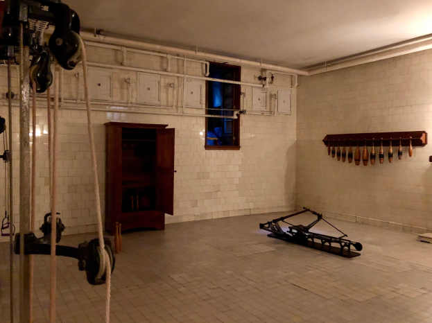 Ein unordentlicher Raum im ehemaligen St. Louis-Gefängnis mit Seilen, Maschinen und anderem Equipment, mit einem Schrank, Fenster und einer Deckenlampe im Hintergrund.