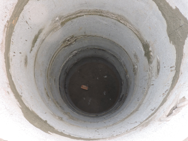 Betonschalung für Abwasserrohr mit mittigem Loch in einer Betonwand und einem Objekt im Loch.