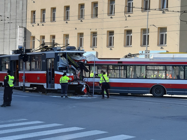 Rote und weiße Straßenbahn krachte auf der Seite der Straße mit ein paar Menschen in der Nähe und einem Gebäude im Hintergrund.