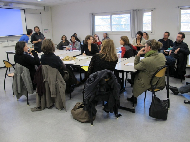 Eine Gruppe von Menschen, die sich unterhält und diskutiert, mit zwei Personen, die separat stehen und sprechen.