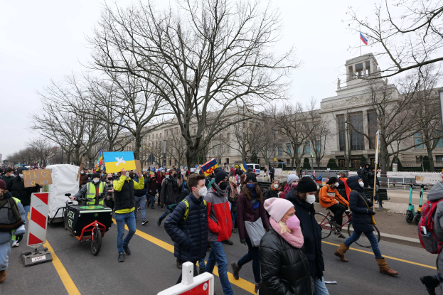 Eine großle Gruppe von Menschen marschiert bei einer Demonstration in Washington, D.C. am 21. Januar 2020, mit Plakaten und Transparenten, einige fahren Fahrräder, mit Bäumen, Schildern und einem klaren blauen Himmel im Hintergrund.