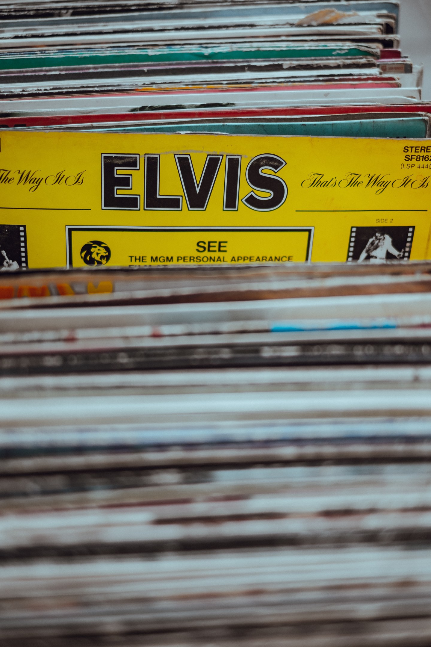 Ein ordentlicher Stapel Elvis Presley-Platten mit sichtbaren Titeln auf einem leicht unscharfen Hintergrund.