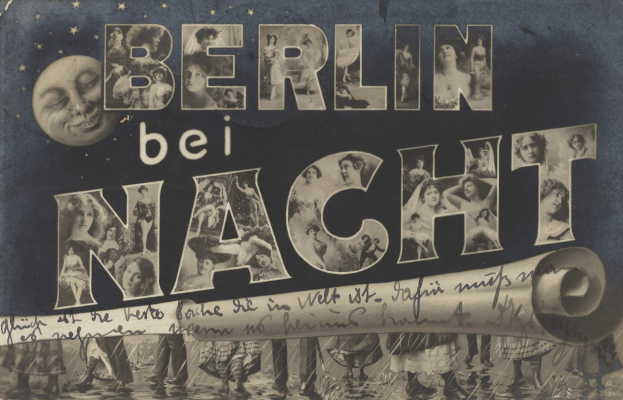 Schwarzes und weißes Foto einer Gruppe von Menschen, die vor einem Schild mit der Aufschrift "Berlin Bei Nacht" mit einem Mond im Hintergrund lachen und strahlen, das Schild ist mit Sternen und Streifen geschmückt.