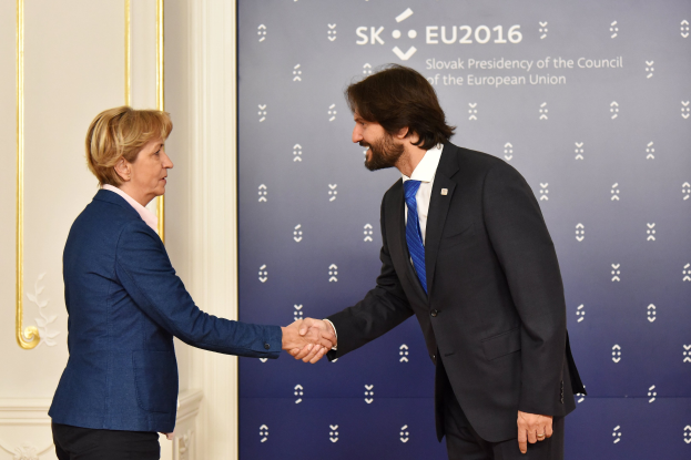 Bundeskanzlerin Angela Merkel und Joachim Gauck schütteln Hände vor einer Wand mit einem "EU-Gipfel"-Banner und einer Tür.