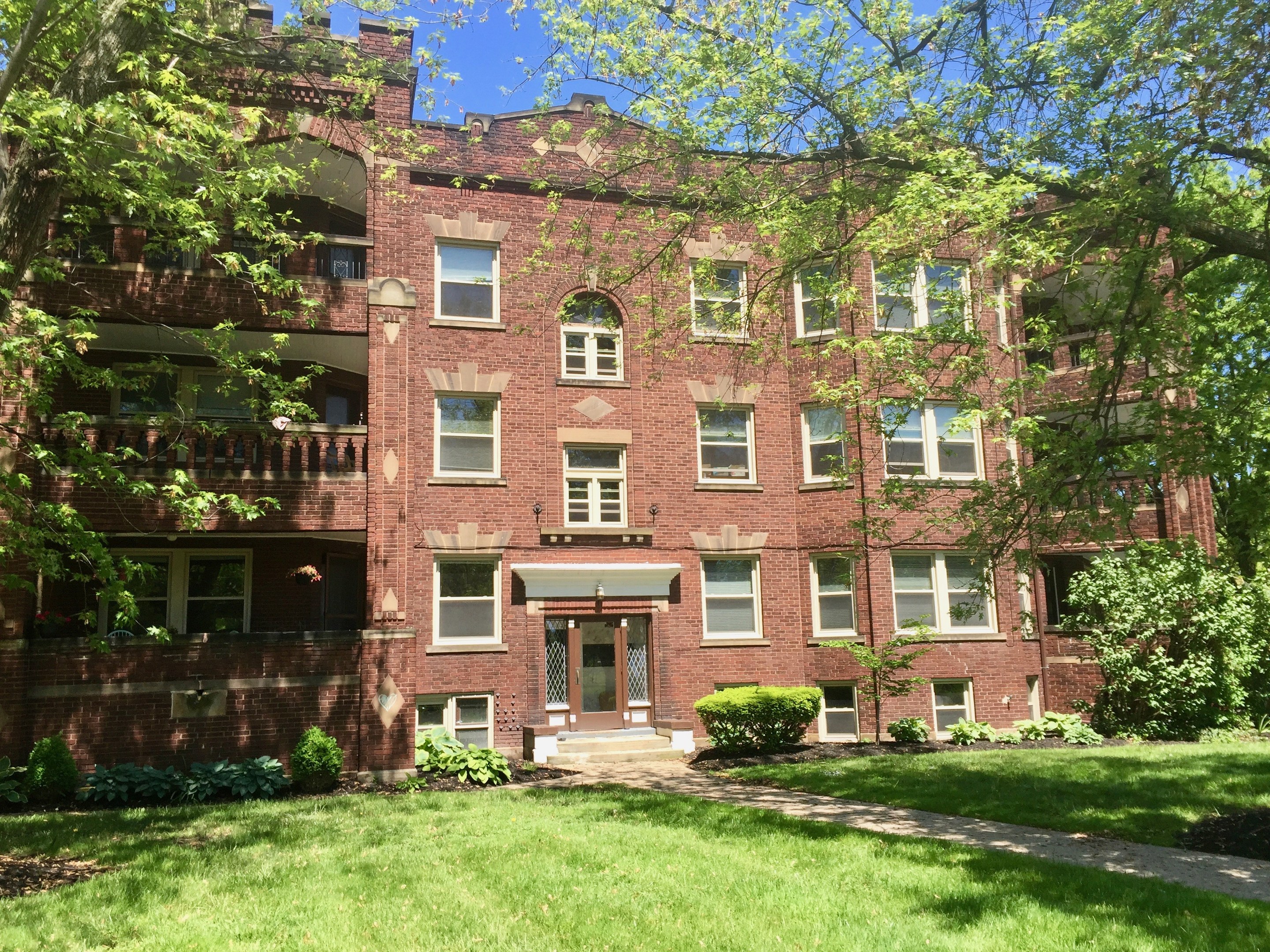 Großes Ziegelsteingebäude mit einem grünen Rasen, Bäumen und Pflanzen davor unter einem klaren blauen Himmel, gelegen in Chicago, Illinois.