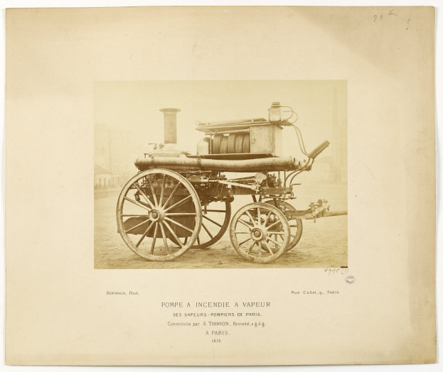 Vintage black and white photo of an old-fashioned fire engine parked in front of a building, surrounded by text.