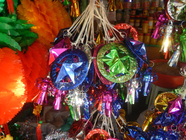 Farbenfrohe Dekorationen, darunter Laternen und Bänder, hängen von der Decke über Regalen mit Flaschen in einer festlichen Atmosphäre.