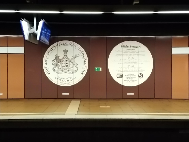 Ein Bahnsteig mit einer 'S-Bahn Stuttgart'-Aufschrift und Logo an der Wand, Deckenleuchten und ein paar Gegenstände auf der linken Seite des Bahnsteigs.
