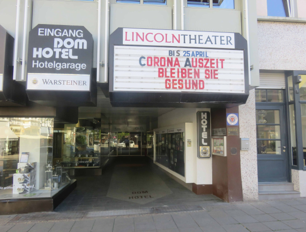 Außenansicht des Lincoln Theaters in Berlin, Deutschland, mit Glasfenstern und -türen sowie einer Schautafel und einem Blick ins Innere.