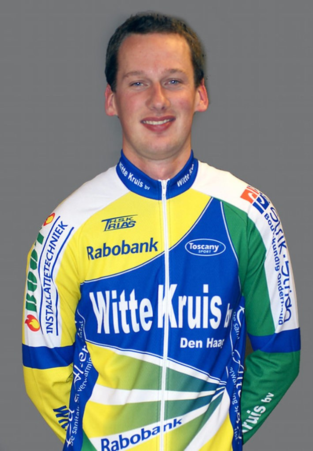 Ein männlicher Athlet posiert für ein Foto, auf dem mehrere Sponsorenlogos zu sehen sind.