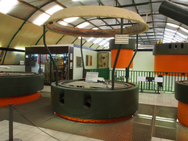 Ein großer Industrieraum mit verschiedenen Maschinen, darunter ein Rotor, eine Kette, Stangen, Texttafeln, ein Zaun, eine Wand, eine Decke und Beleuchtung.