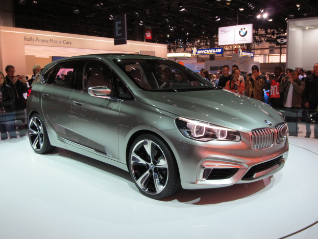 BMW 2er Active Tourer Concept auf der IAA in Frankfurt zu sehen, umgeben von Menschen, die es fotografieren, mit Deckenbeleuchtung und Informationsschildern im Hintergrund.